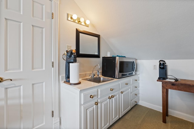 bathroom featuring vaulted ceiling, a sink, a textured ceiling, and baseboards