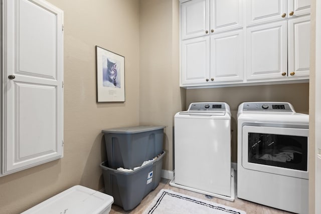 washroom featuring washing machine and dryer and cabinet space