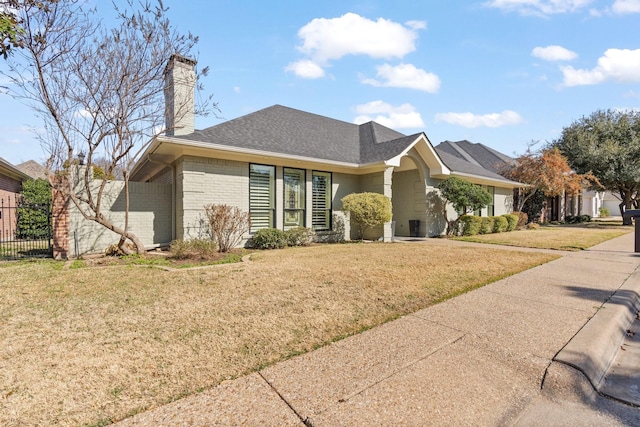 ranch-style home featuring brick siding, roof with shingles, a chimney, fence, and a front lawn