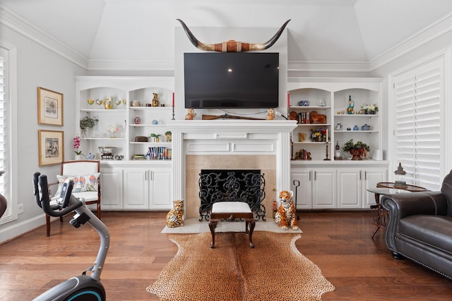 living area with lofted ceiling, a fireplace with flush hearth, built in shelves, and wood finished floors