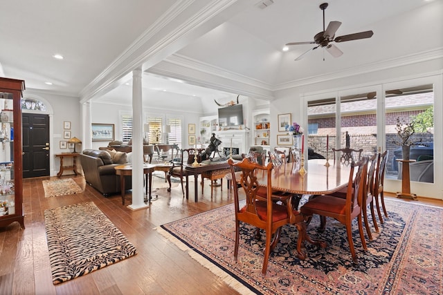 dining room with a fireplace, decorative columns, light wood-style floors, a ceiling fan, and ornamental molding