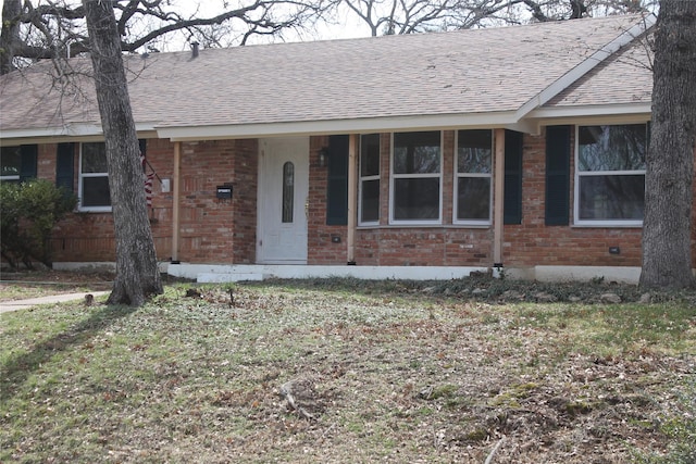 ranch-style home with roof with shingles and brick siding