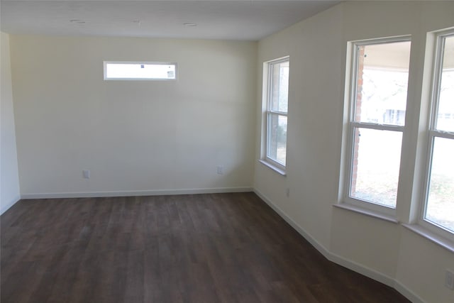 empty room with baseboards, dark wood-style floors, and a healthy amount of sunlight