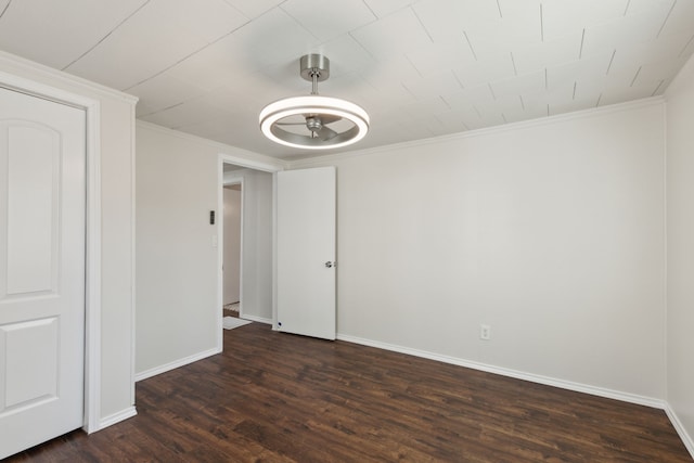 empty room featuring dark wood-style flooring, crown molding, and baseboards