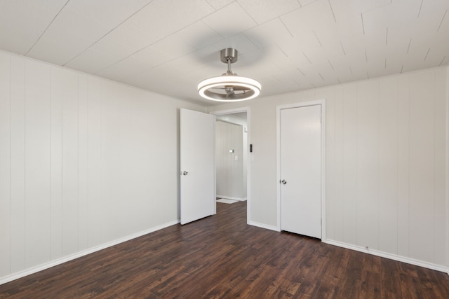 spare room featuring dark wood-style floors and baseboards