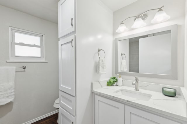 bathroom featuring toilet, vanity, baseboards, and wood finished floors