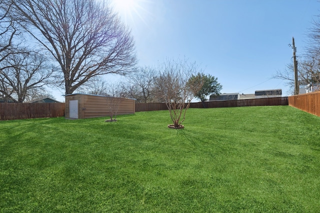 view of yard featuring a fenced backyard, a shed, and an outbuilding