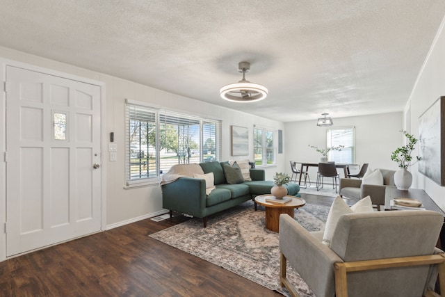 living room with visible vents, a textured ceiling, baseboards, and dark wood-type flooring