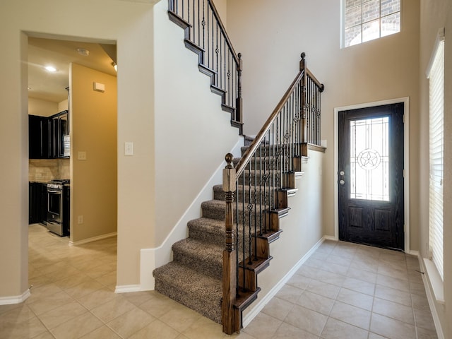 entrance foyer with a towering ceiling, light tile patterned floors, baseboards, and recessed lighting