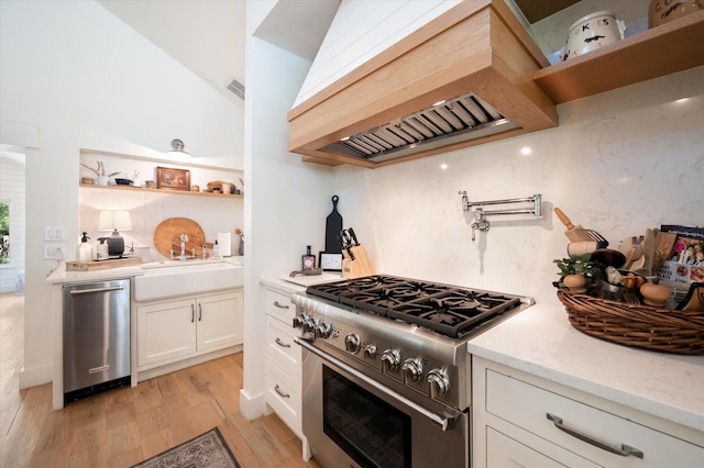 kitchen featuring stainless steel appliances, premium range hood, a sink, white cabinets, and open shelves