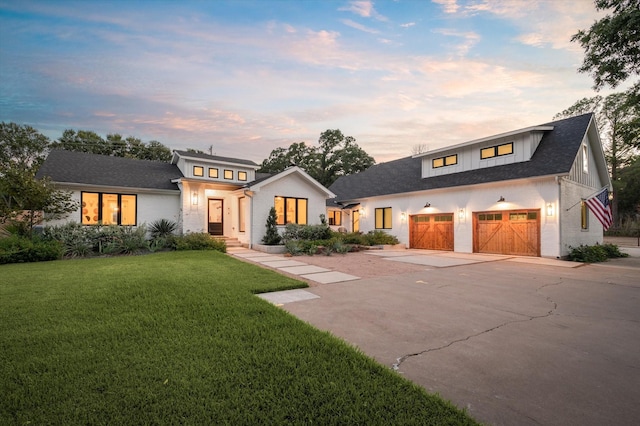 modern inspired farmhouse with driveway, brick siding, a garage, and a front yard