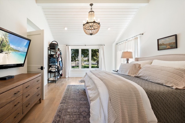 bedroom featuring lofted ceiling, light wood finished floors, and a notable chandelier