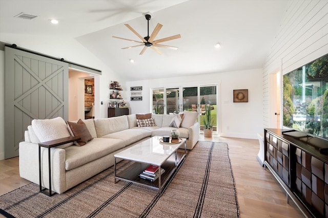 living room featuring a ceiling fan, plenty of natural light, light wood finished floors, and a barn door