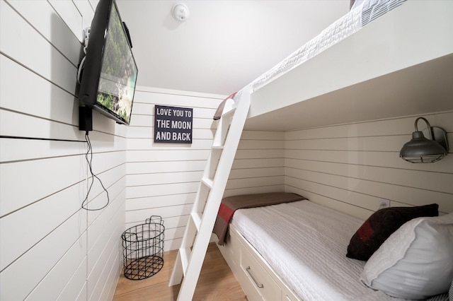 bedroom featuring light wood-style floors and wood walls