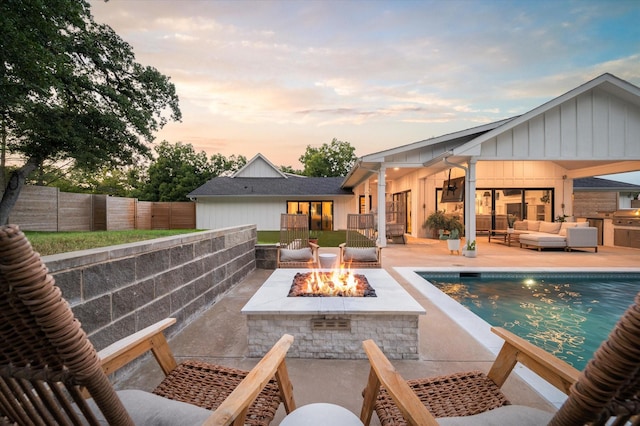 rear view of house featuring a fenced in pool, an outdoor living space with a fire pit, a fenced backyard, a patio area, and board and batten siding