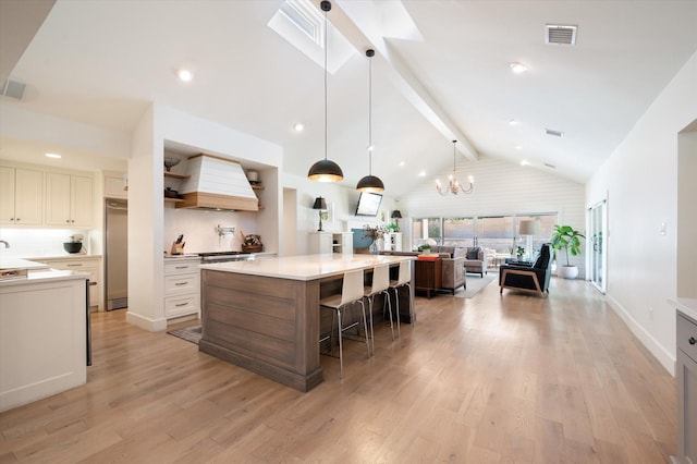 kitchen featuring visible vents, a kitchen breakfast bar, light countertops, open shelves, and custom range hood