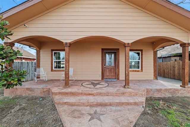 property entrance with fence, a porch, and a patio