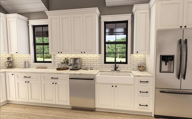 kitchen featuring a sink, decorative backsplash, white cabinetry, and stainless steel appliances