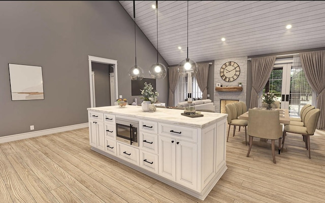 kitchen with a kitchen island, white cabinets, built in microwave, high vaulted ceiling, and pendant lighting