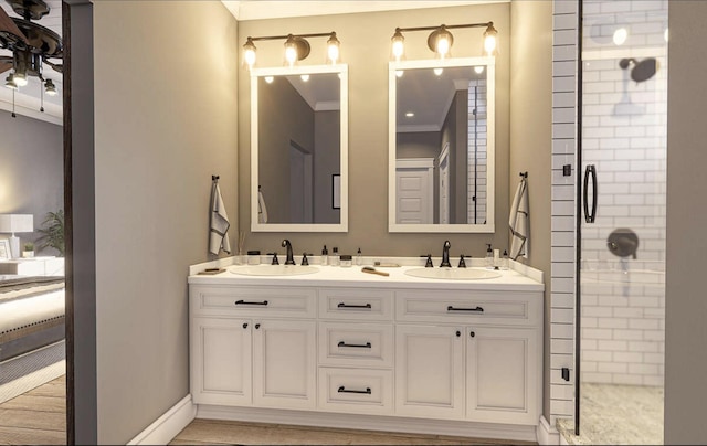 full bathroom with a shower stall, double vanity, a sink, and ornamental molding