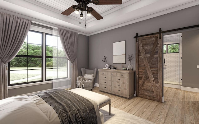 bedroom with a barn door, light wood-style floors, a tray ceiling, and baseboards