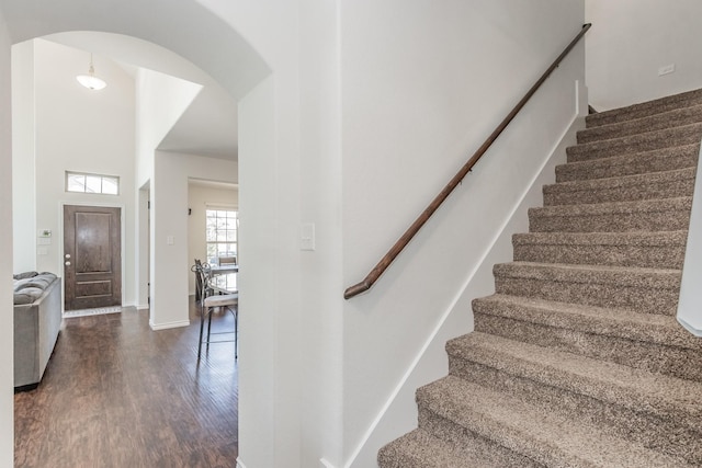 staircase with arched walkways and wood finished floors