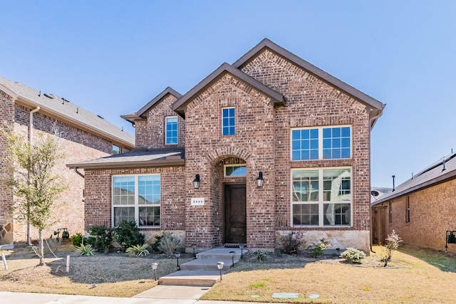 traditional home featuring a front yard and brick siding