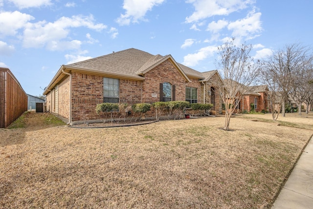 single story home with a front yard, brick siding, fence, and roof with shingles