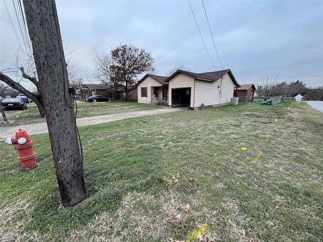 exterior space with driveway, an attached garage, cooling unit, and a front yard