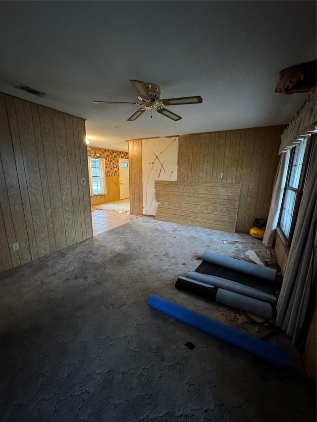 spare room featuring carpet, visible vents, ceiling fan, and wooden walls