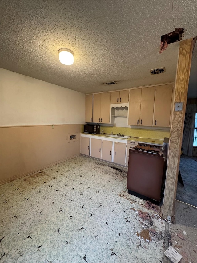 kitchen featuring black microwave, visible vents, range with gas stovetop, light countertops, and light floors