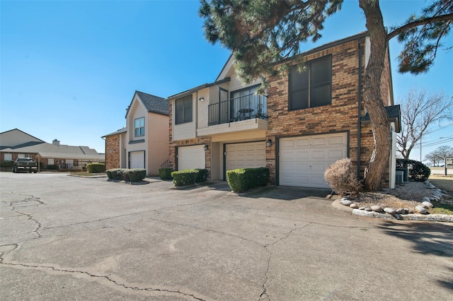 multi unit property featuring brick siding, driveway, and an attached garage