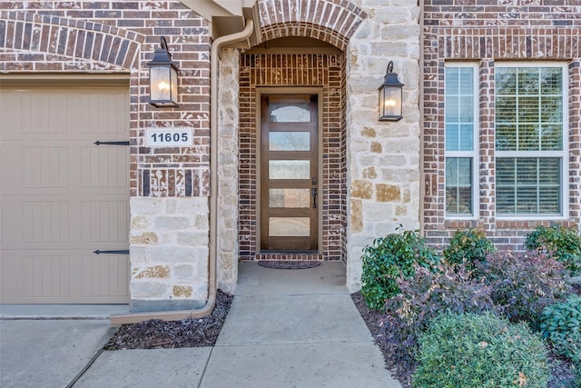 doorway to property with a garage, stone siding, and brick siding