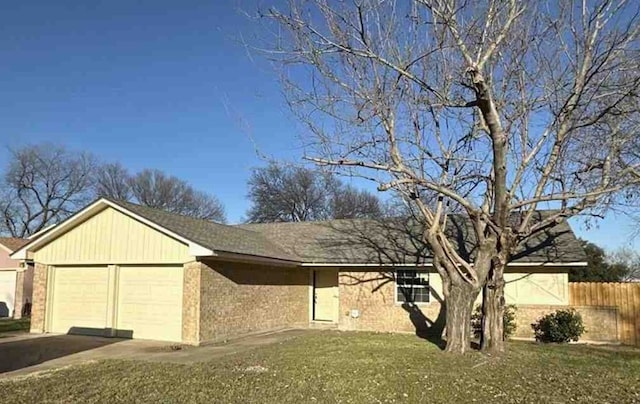 ranch-style home featuring an attached garage, fence, a front lawn, and brick siding