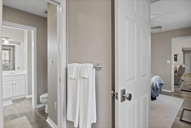 ensuite bathroom featuring visible vents, baseboards, toilet, wood finished floors, and vanity