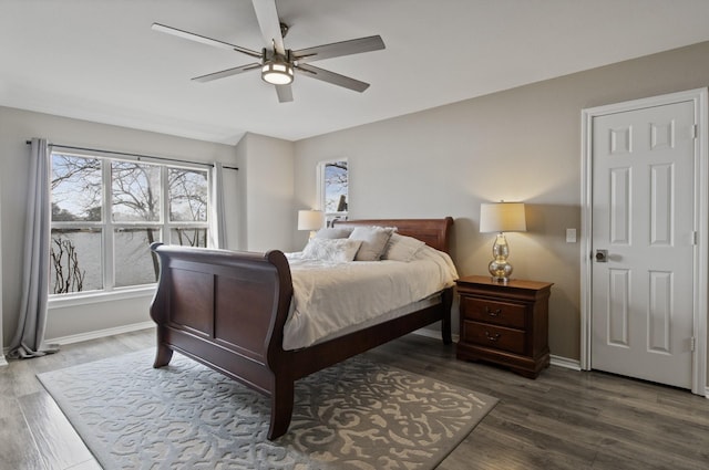 bedroom featuring dark wood-type flooring, a ceiling fan, and baseboards