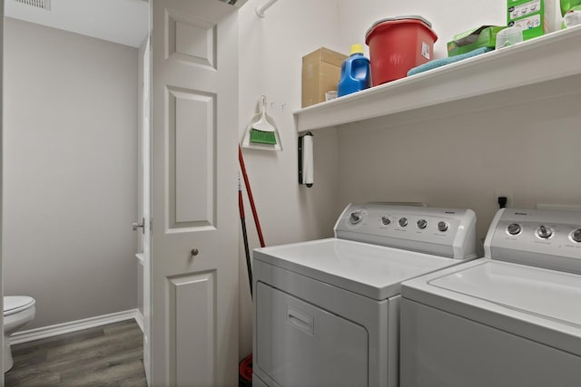 laundry room with dark wood-type flooring, washing machine and dryer, and baseboards