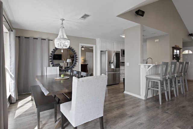 dining room with dark wood-style floors, visible vents, and a notable chandelier