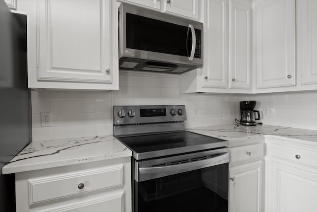 kitchen featuring stainless steel appliances, tasteful backsplash, light stone counters, and white cabinets