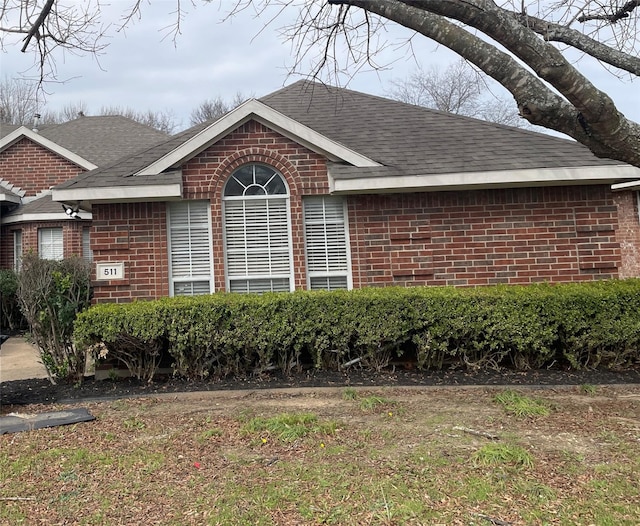 view of property exterior featuring brick siding and roof with shingles