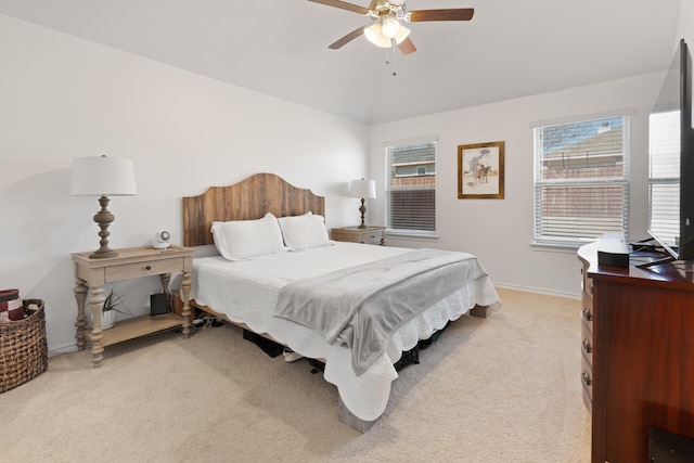 bedroom with a ceiling fan, light carpet, and baseboards