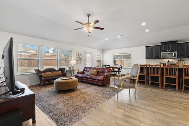 living room with a ceiling fan, a wealth of natural light, vaulted ceiling, and recessed lighting