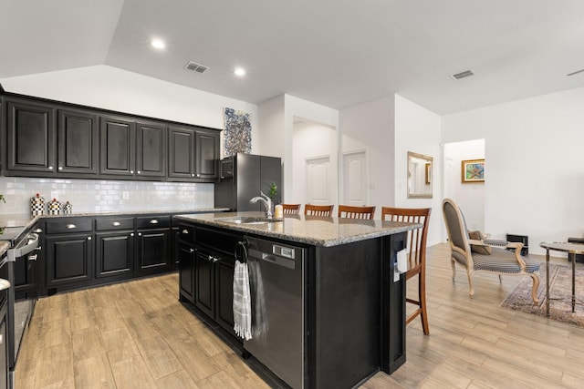 kitchen featuring visible vents, an island with sink, a breakfast bar area, stainless steel appliances, and a sink