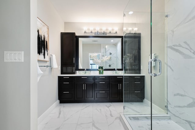 bathroom featuring a sink, baseboards, marble finish floor, a marble finish shower, and double vanity