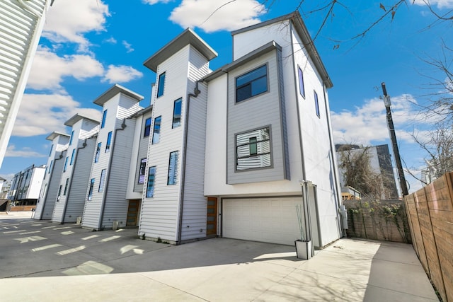 view of front of house featuring a residential view, fence, and concrete driveway