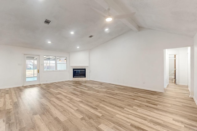 unfurnished living room featuring vaulted ceiling with beams, light wood finished floors, a glass covered fireplace, and visible vents