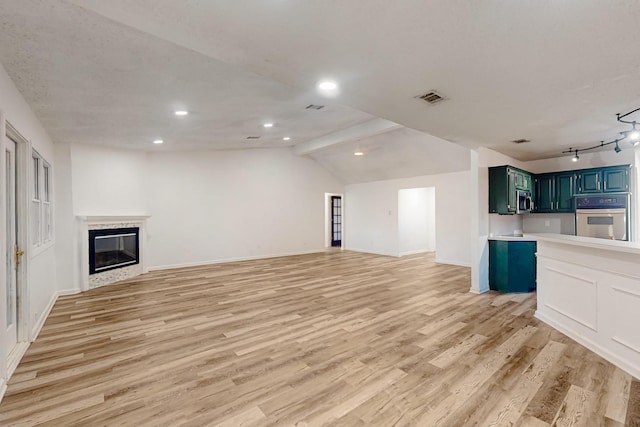 unfurnished living room featuring vaulted ceiling with beams, visible vents, a glass covered fireplace, light wood-type flooring, and baseboards