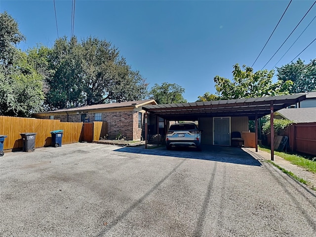 view of side of property featuring fence, aphalt driveway, a carport, and brick siding