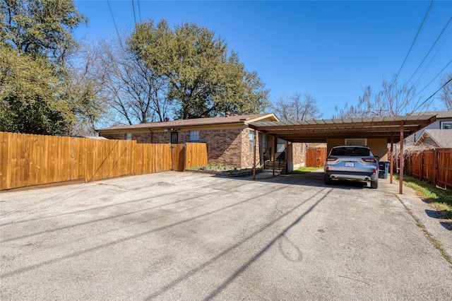 view of front of property with driveway, fence, a carport, and brick siding