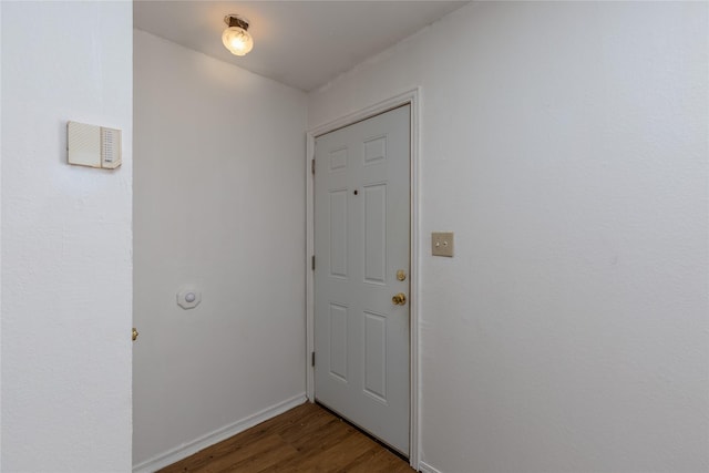 doorway featuring baseboards and dark wood-type flooring